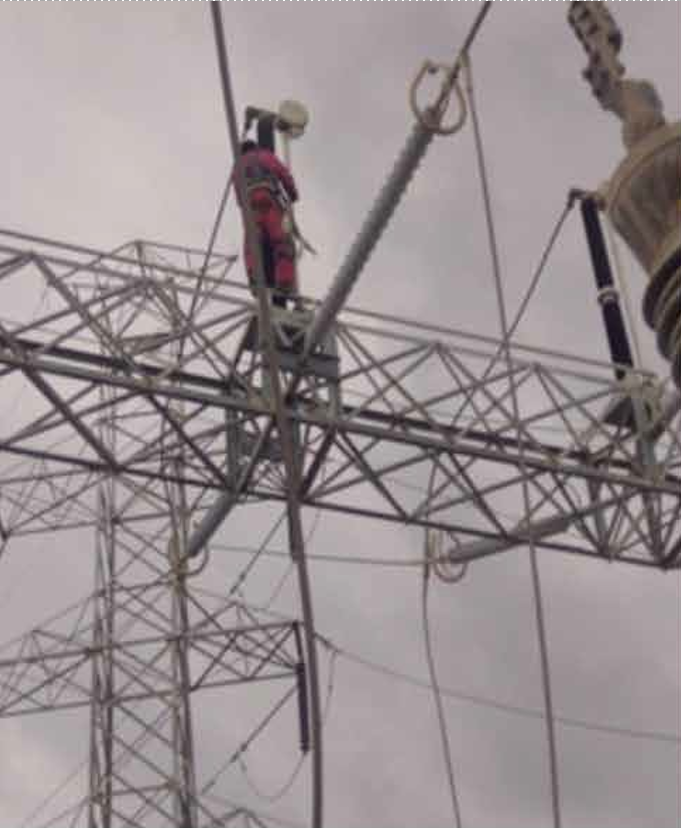 Operario en torre de transmisión eléctrica realizando mantenimiento