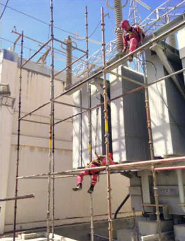 Personal en andamios junto a transformador o equipo eléctrico industrial