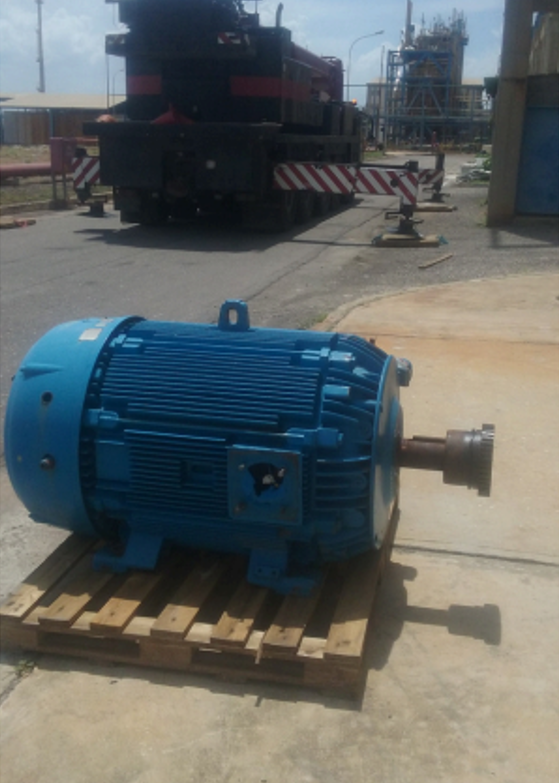 Motor eléctrico industrial azul sobre palé en área de planta petroquímica