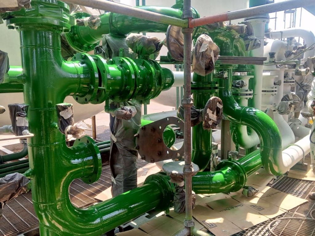 Tuberías industriales verdes recién pintadas en planta petroquímica