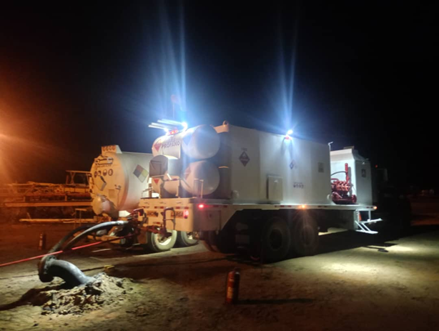 Unidad de servicio industrial iluminada operando de noche en campo petrolero