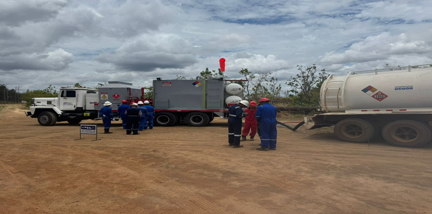 Personal con EPP junto a unidades de servicio y cisterna en campo petrolero